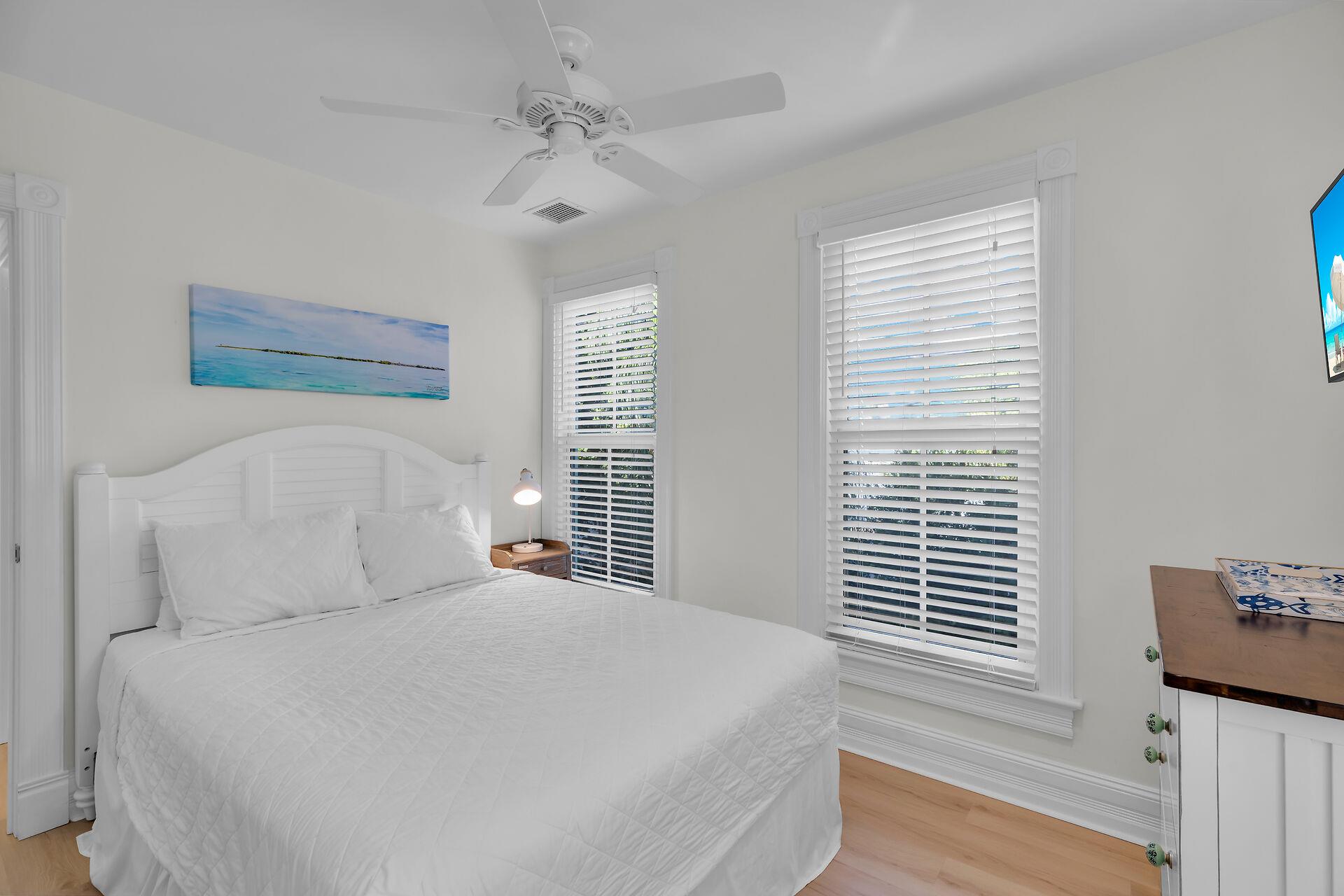 Queen guest bedroom with ceiling fan and dresser.