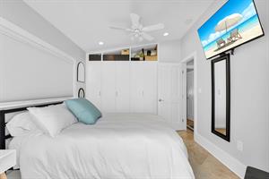 Guest bedroom with queen bed, closet and TV