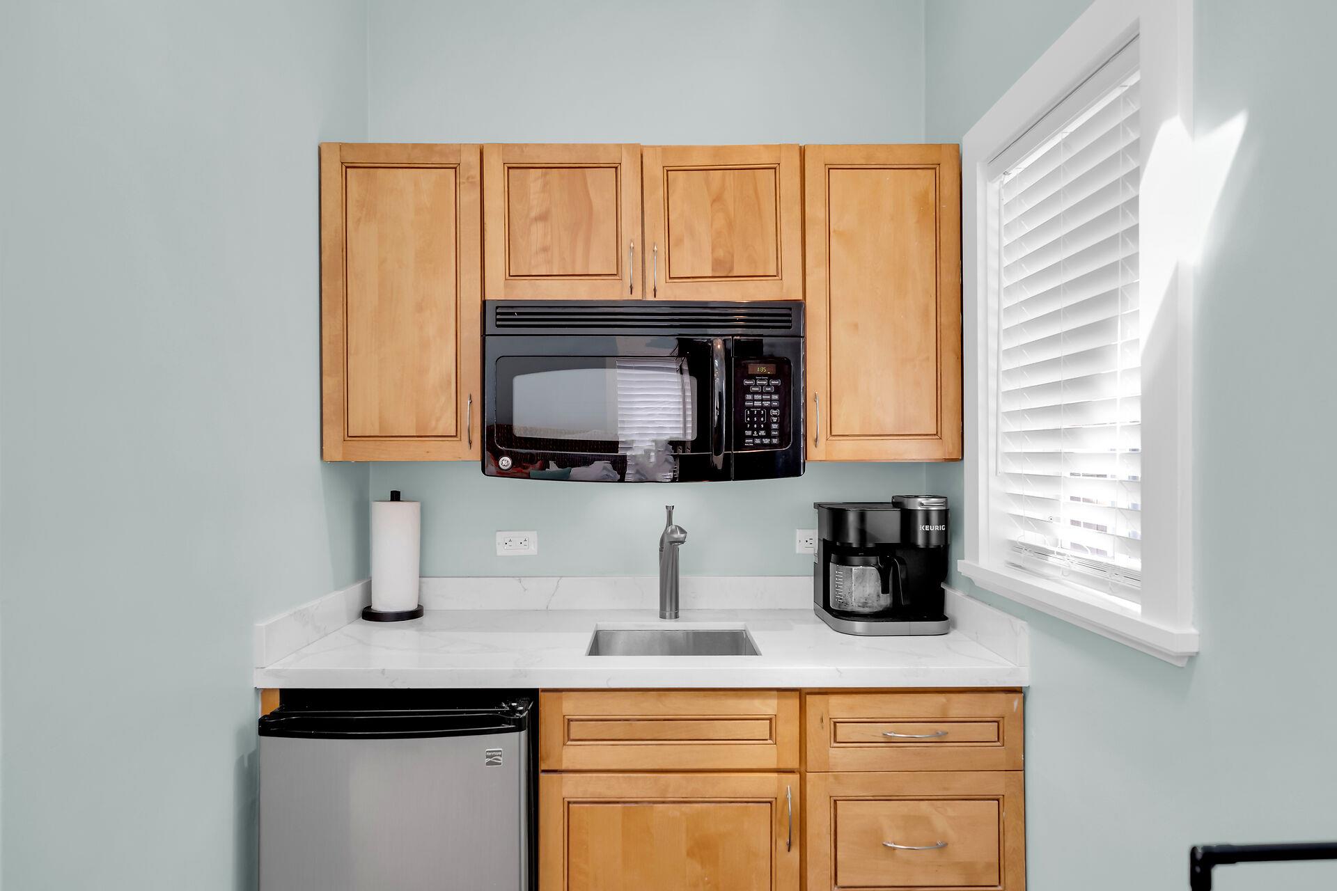 Kitchenette has a sink, mini refrigerator, and microwave