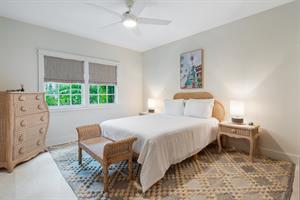 First floor queen bedroom with dresser, TV, and ceiling fan.