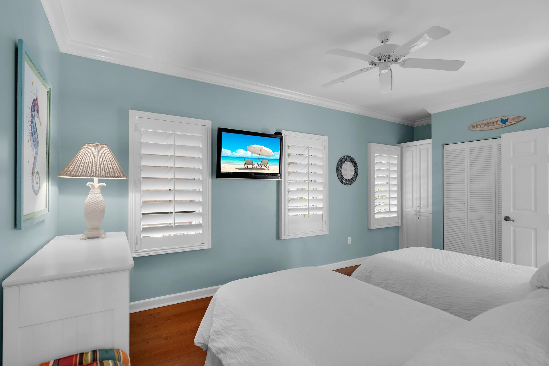 Guest bedroom with TV, ceiling fan, dresser and closet.
