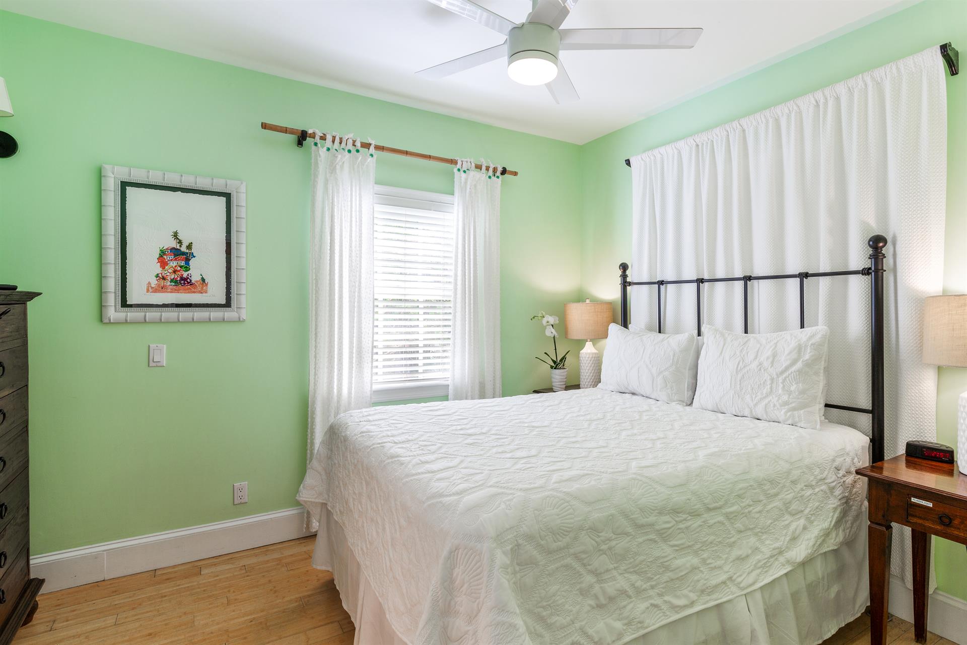 Queen bed with ceiling fan and bedside lighting.