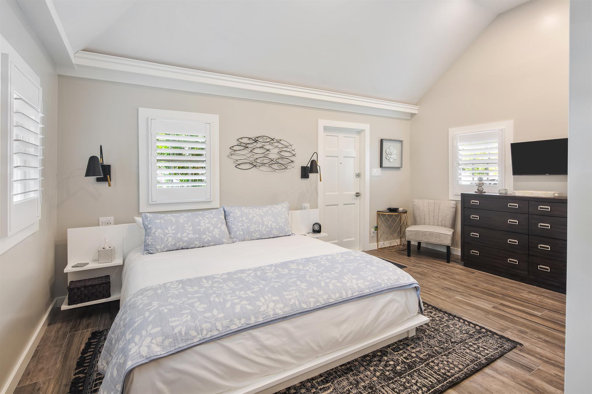 Dresser, TV, and bedside wall lights in this primary bedroom