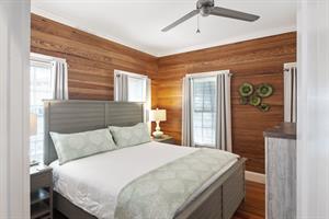 First floor bedroom includes king bed, dresser, and TV