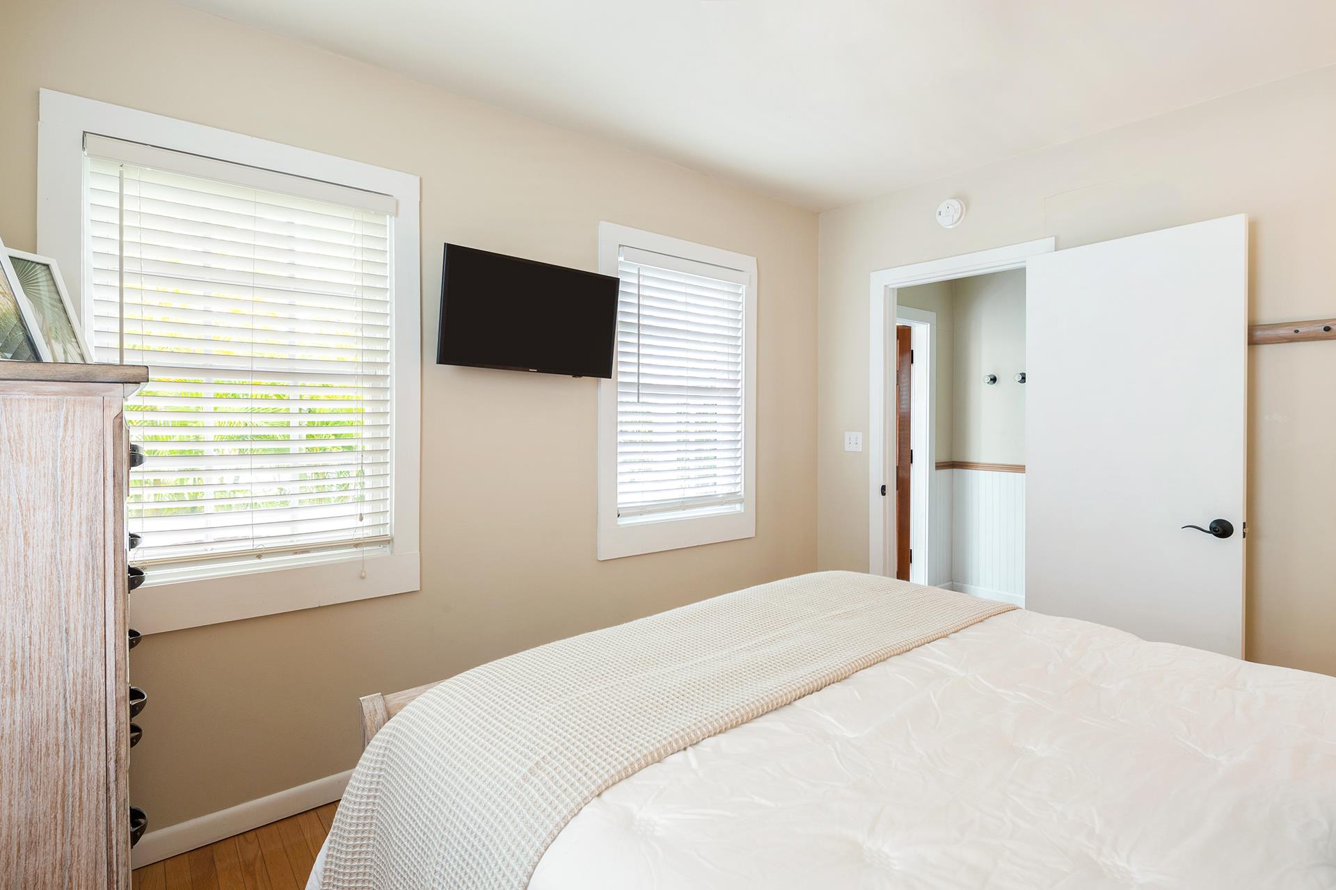 Queen bed with TV, dresser, and plenty of light.