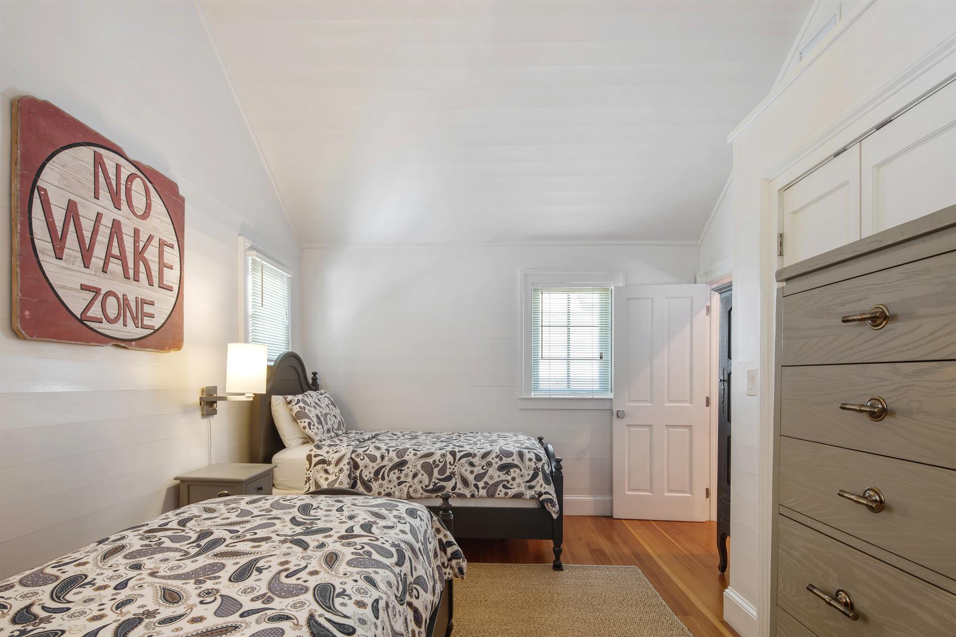 Twin bedroom offers dresser, closet and bedside lighting