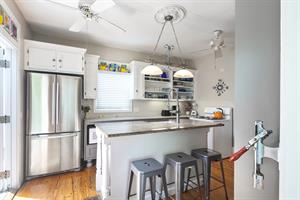 Kitchen includes stainless steel fridge and white, bright finish