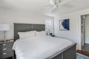King bedroom with bedside storage and ceiling fan.
