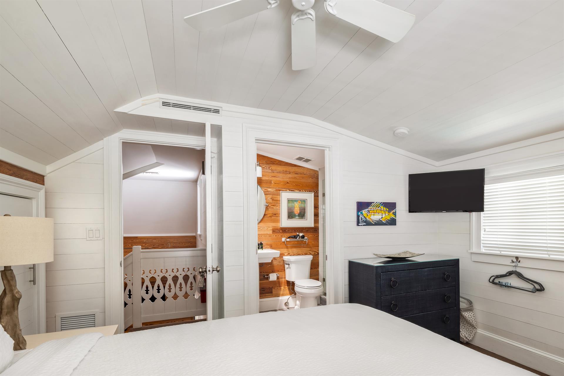 Second floor queen bedroom with dresser, TV, and ceiling fan.