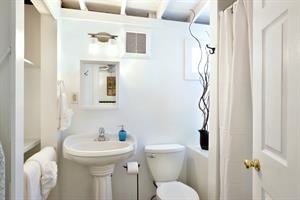 Bathroom has tiled shower and pedestal sink.