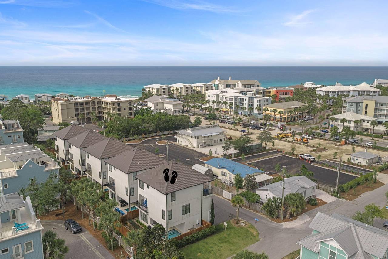 Aerial view of a coastal residential community nestled among palm trees, just steps from turquoise Gulf waters.