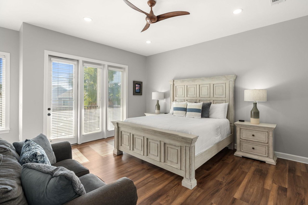 Bedroom 1 is a sanctuary with luxurious linens, a cozy reading chair, and French doors opening to a Balcony