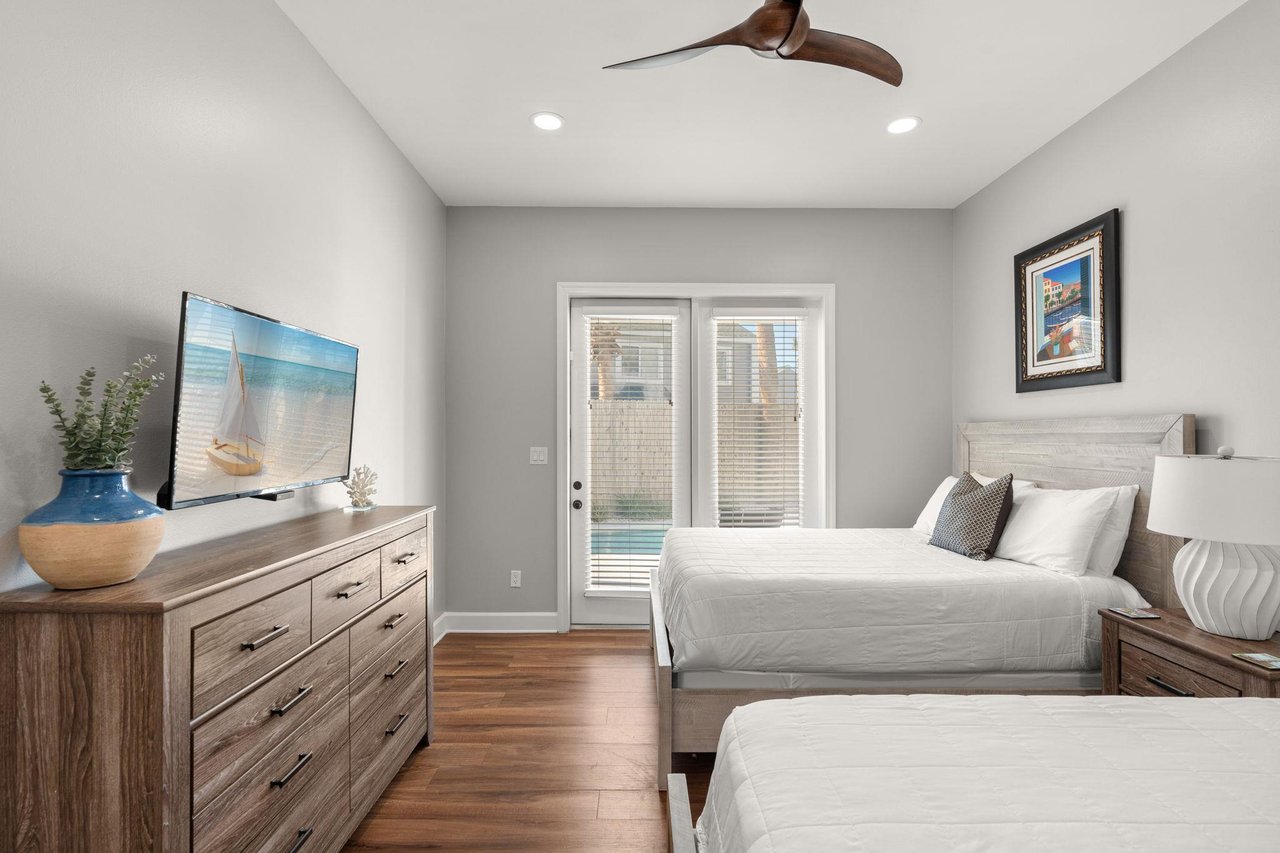 Relax in the serene bedroom with twin beds, warm wood floors, and French doors opening to your private pool area.