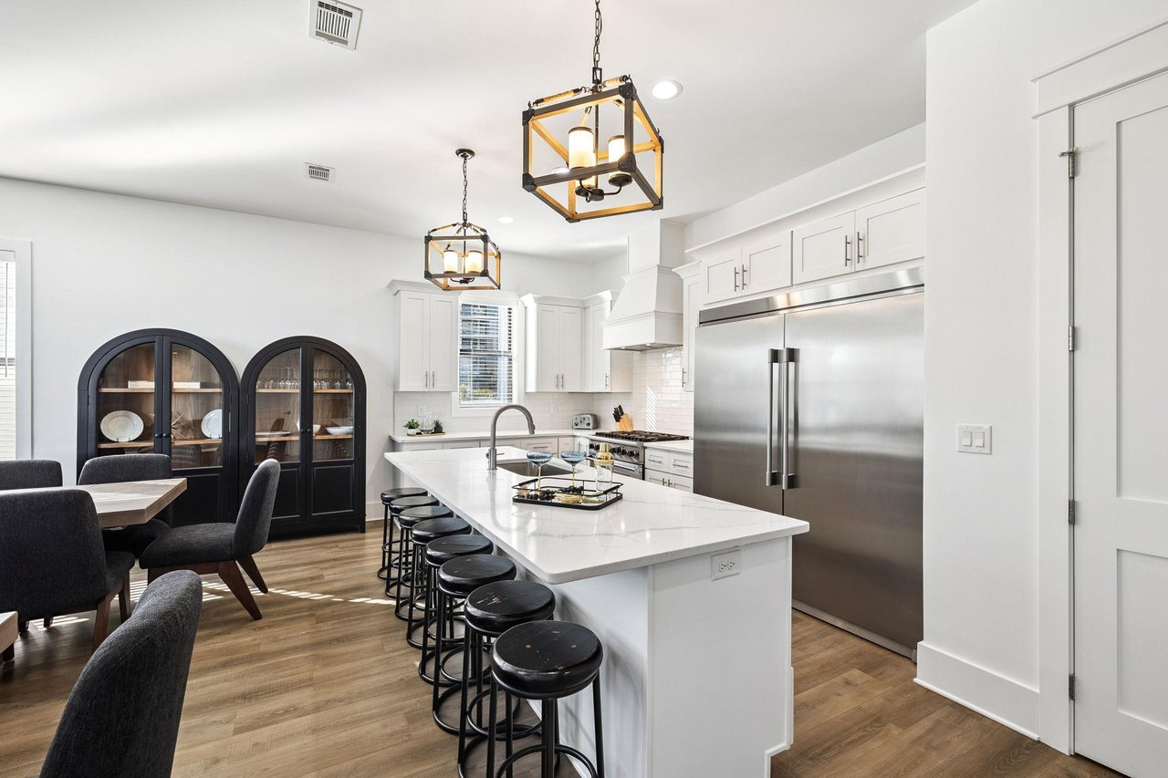 The open kitchen invites culinary adventures with a large island, stainless steel appliances, and elegant pendant lighting.