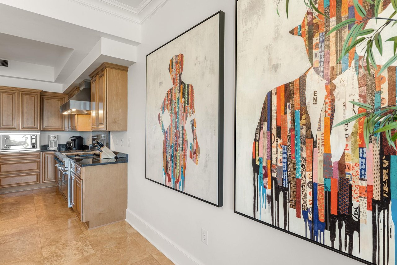 Step into this stylish kitchen where vibrant artwork meets sleek granite countertops and warm wood cabinets, creating the perfect space for culinary adventures.