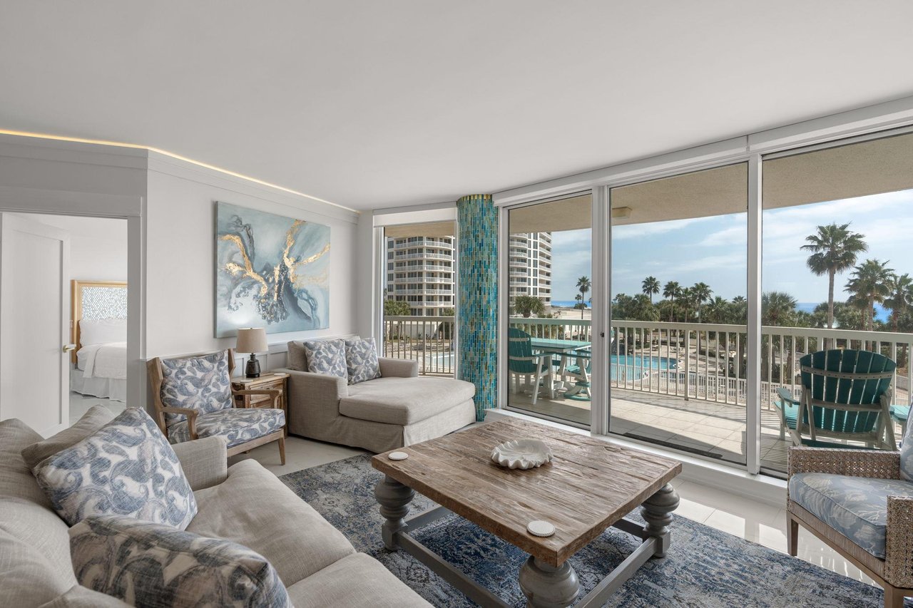 Unwind in your elegant living space with panoramic windows framing tropical palms and azure pools below.