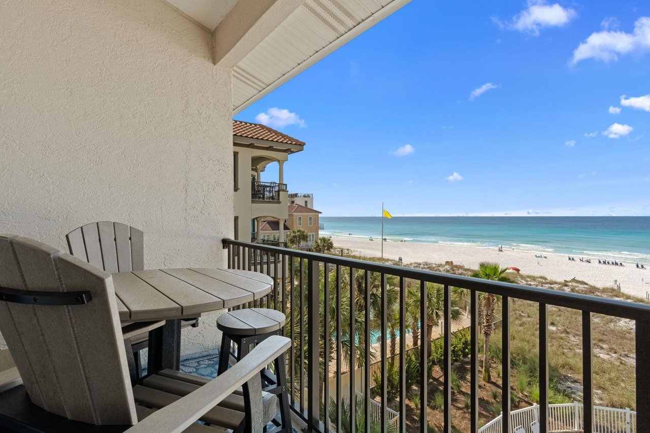Balcony overlooking pristine white sand beach and turquoise Gulf waters, with seating perfect for morning coffee or sunset views.