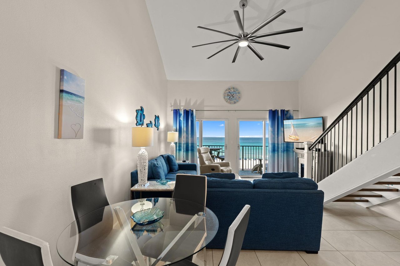 Your spacious living area features ocean views through the balcony doors, plush navy seating, a dining table, and coastal décor that sets a breezy, relaxing tone for your stay.