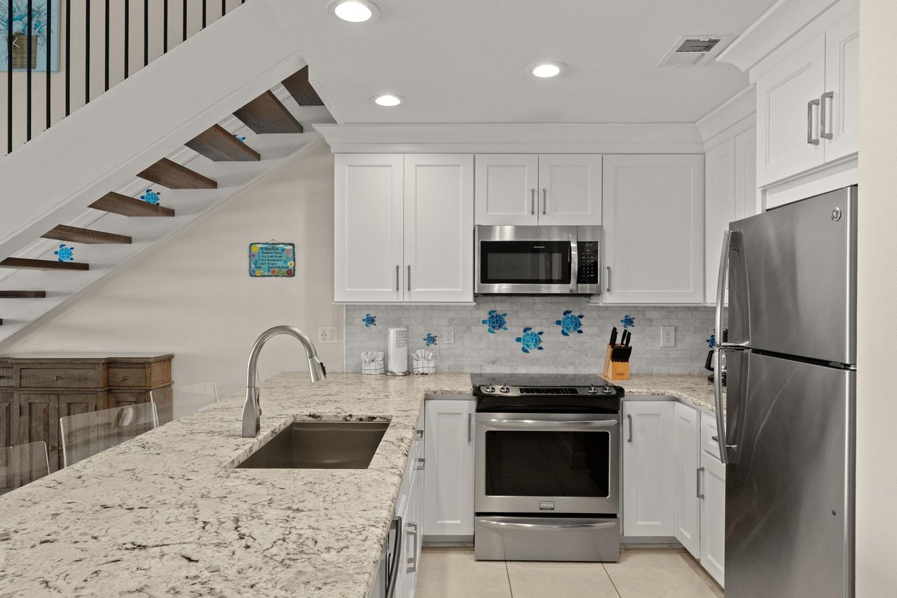 Your bright, modern kitchen features granite countertops, stainless steel appliances, and charming coastal decor—perfect for preparing meals or brewing morning coffee in your home away from home.