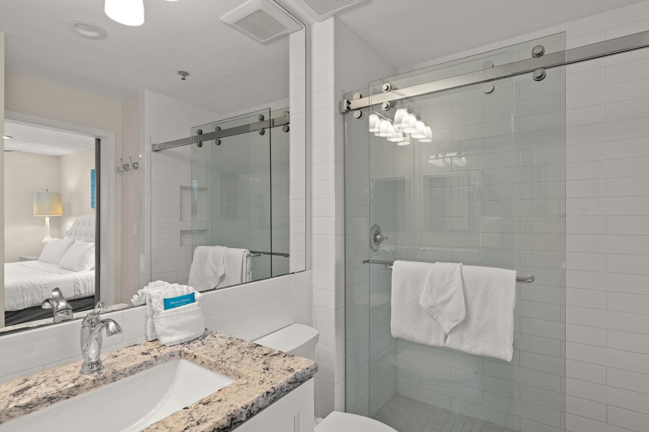 Spacious walkin shower with sleek glass doors, elegant subway tile, and soft towels waiting for you. The granite vanity and modern fixtures create a luxurious space to refresh and unwind.