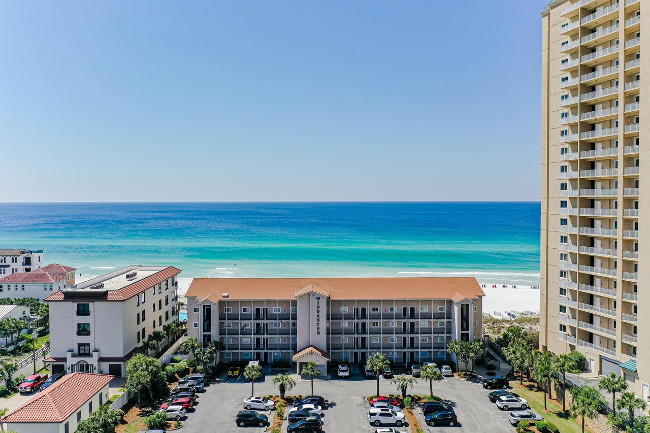 Fourstory beachside property with parking area in a coastal resort community. The property features direct beach access and overlooks the turquoise Gulf waters.