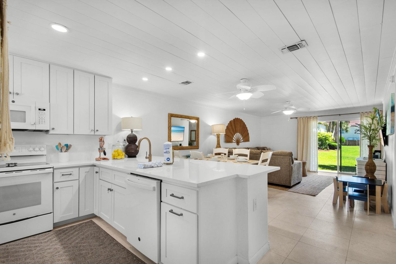 Your openconcept retreat features a bright coastal kitchen flowing into a relaxed living space, with views of lush greenery just outside your door.