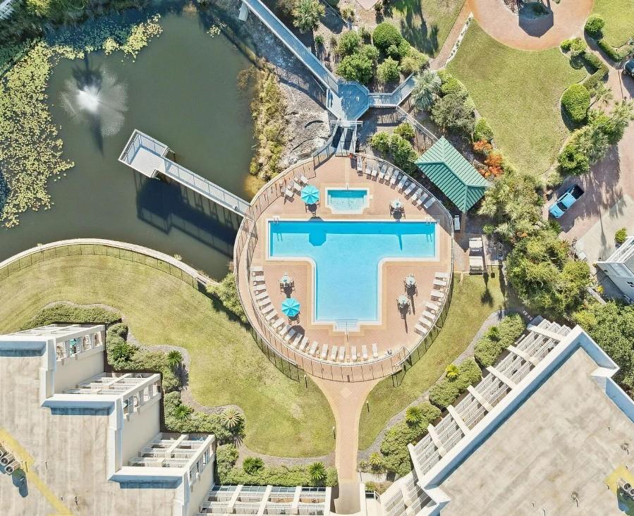 Aerial view showcasing the resorts distinctive crossshaped pool, surrounded by lush gardens, waterfront access, and modern accommodations—a tranquil retreat nestled between green lawns and natural w