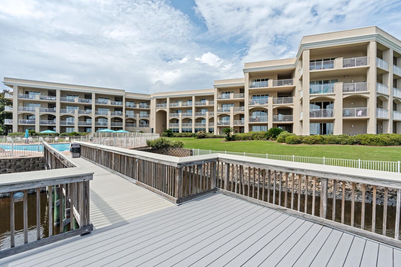 Threestory property features tiered architecture with multiple balconies, manicured lawn, swimming pool, and waterfront access via private boardwalks.