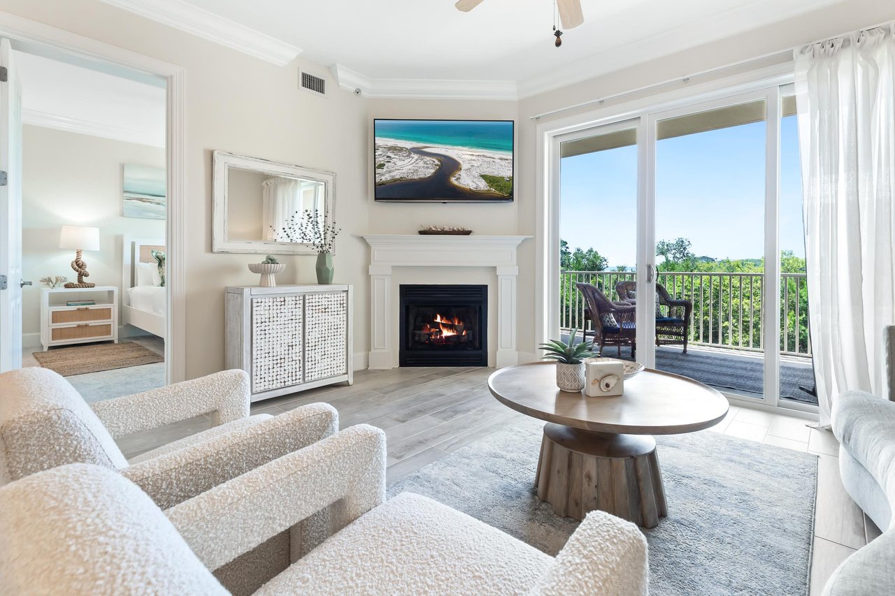 Step into your bright, coastalchic living room where plush seating and a cozy fireplace invite you to relax after sunsoaked days. Large windows frame your private balcony views of endless greenery.