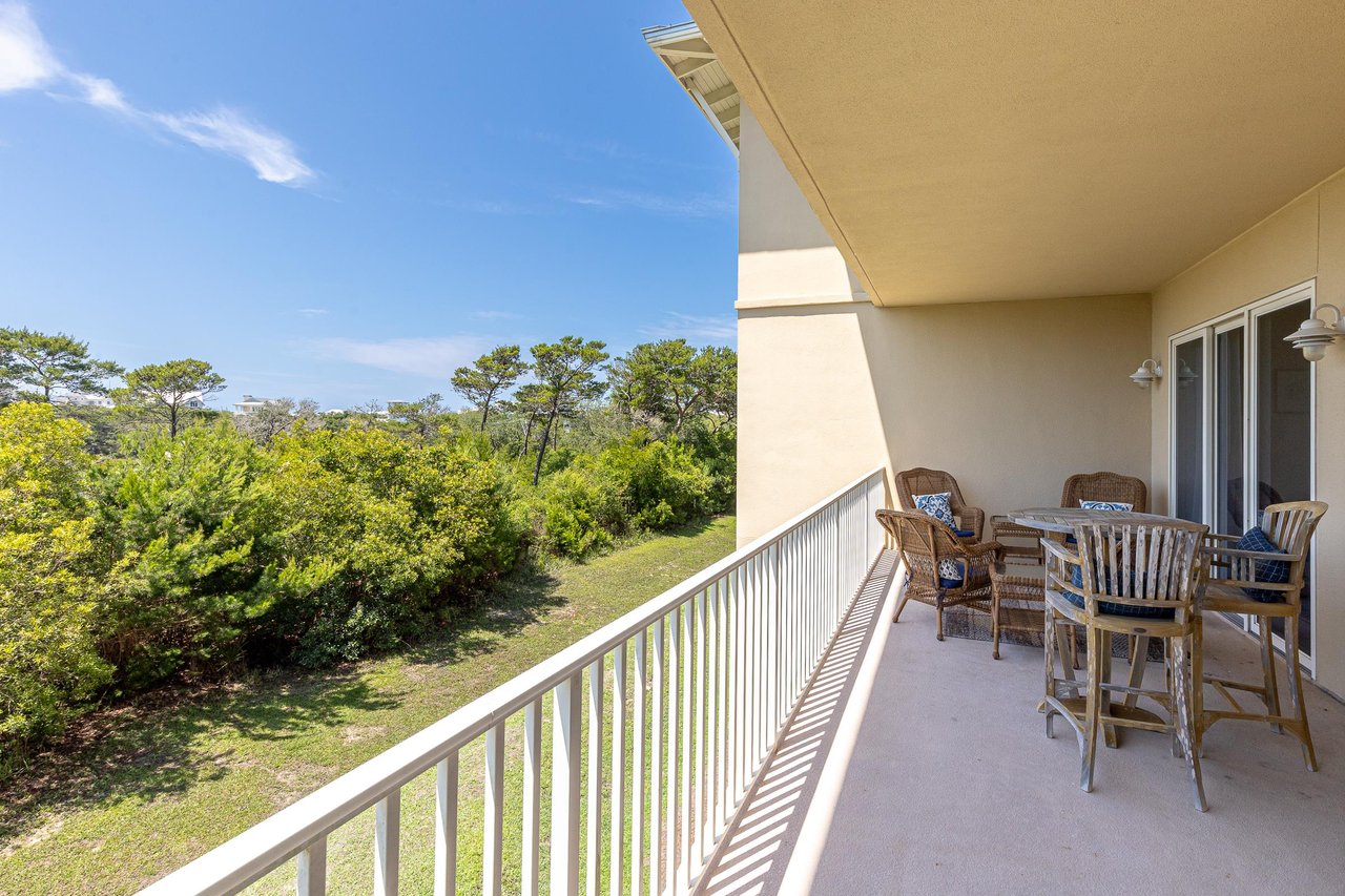 A spacious outdoor terrace overlooks lush coastal greenery under clear blue skies, offering the perfect spot to dine al fresco or simply unwind.