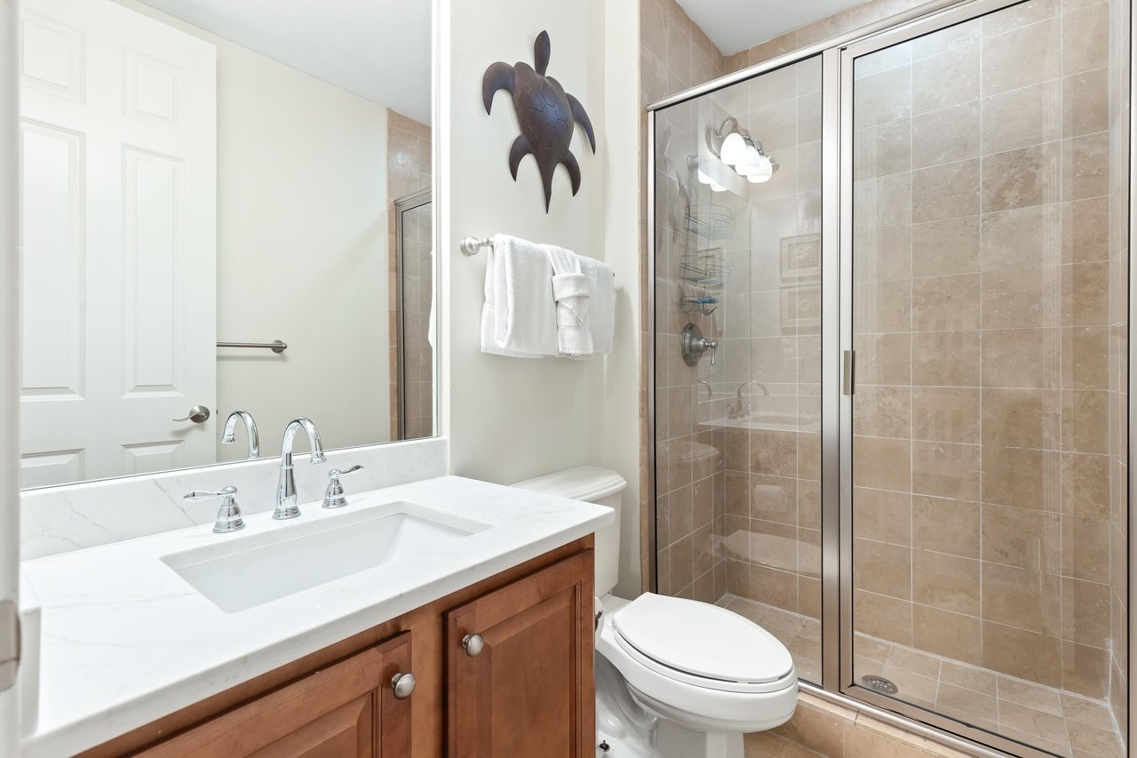 Your private bathroom features a spacious walkin shower, fresh linens, and coastal charm with warm tile accents throughout.