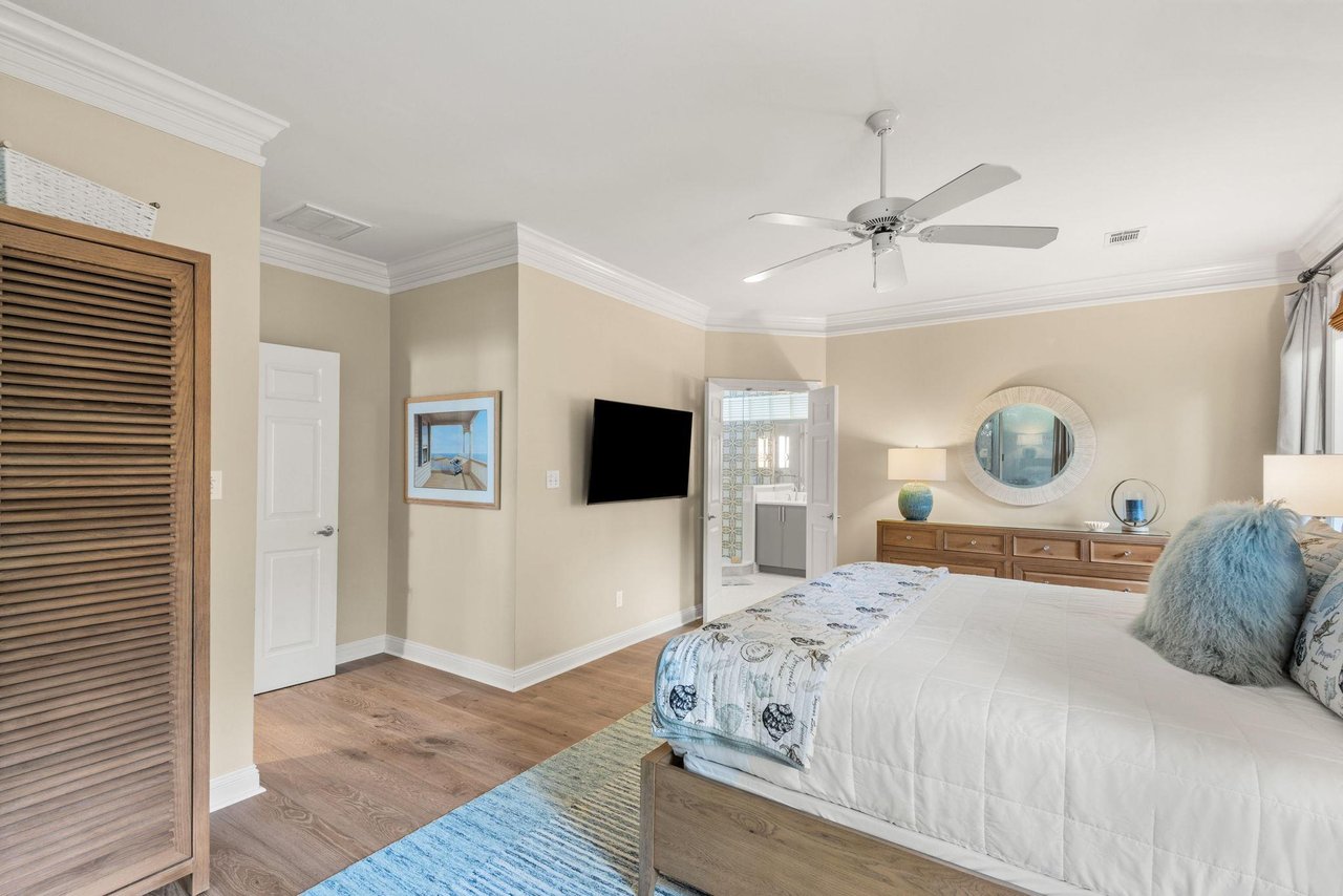 Relax in the primary bedroom with soothing coastal tones, soft linens, and warm wood floors.
