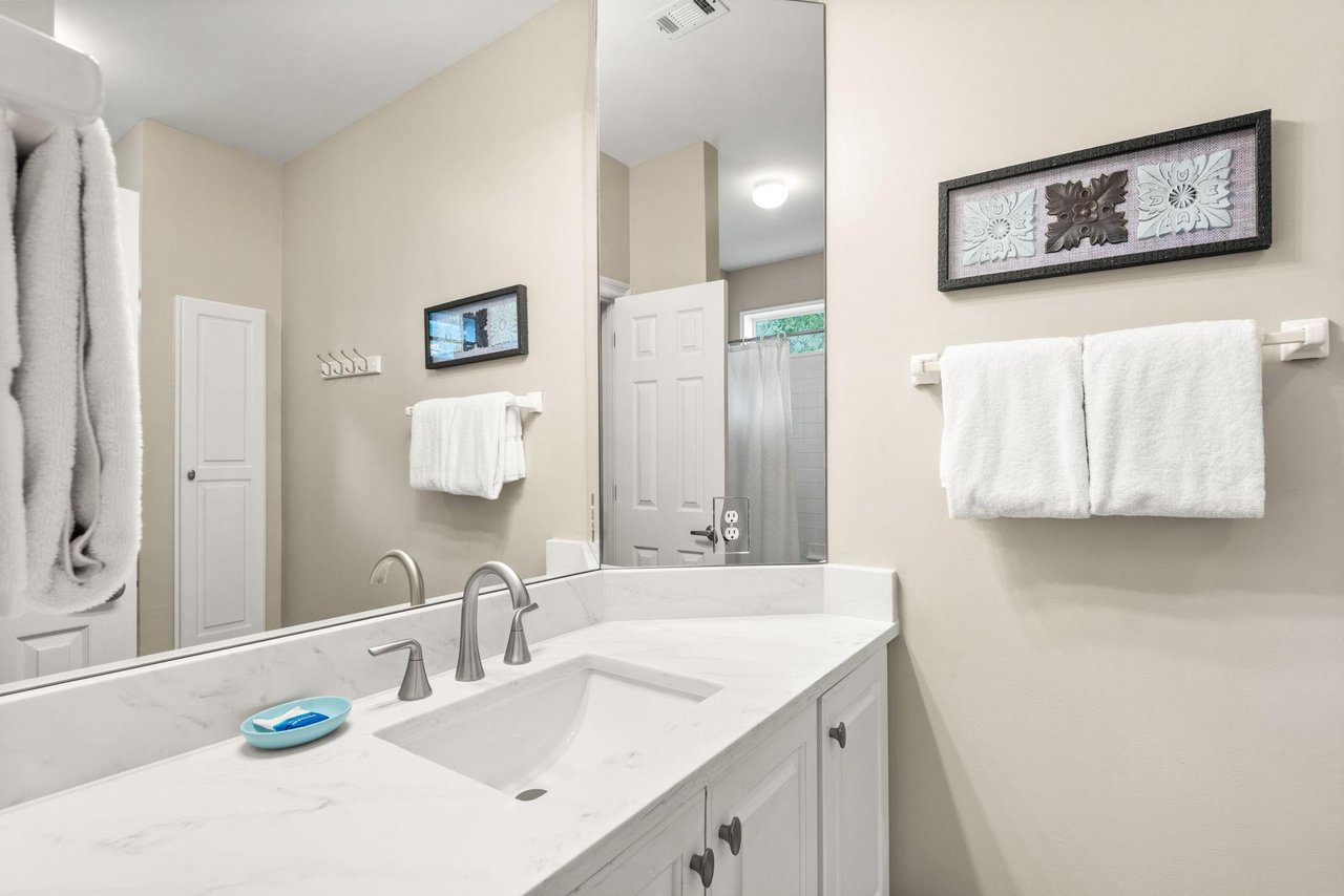 Freshen up in the bathroom, complete with a vanity sink, gleaming countertops, and plush white towels,