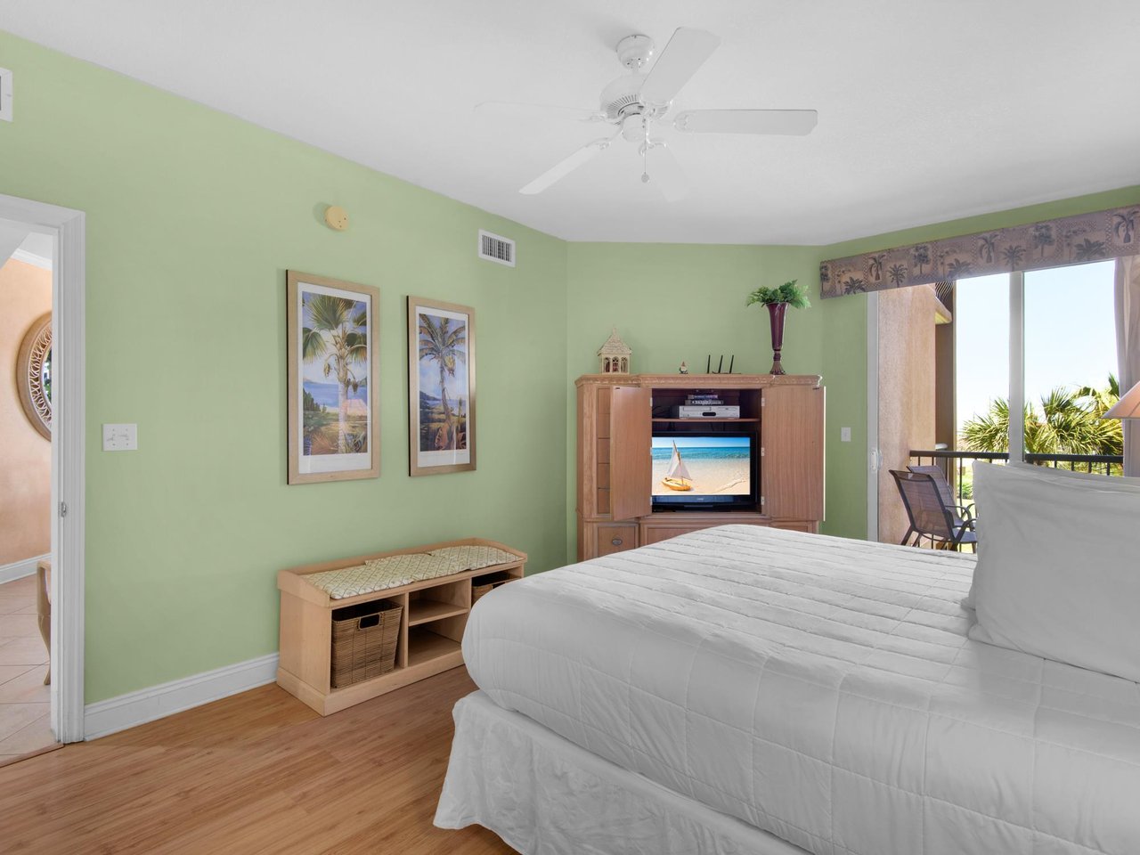 The serene bedroom with ceiling fan comfort and entertainment at your fingertips. Sliding doors lead  to the private balcony.