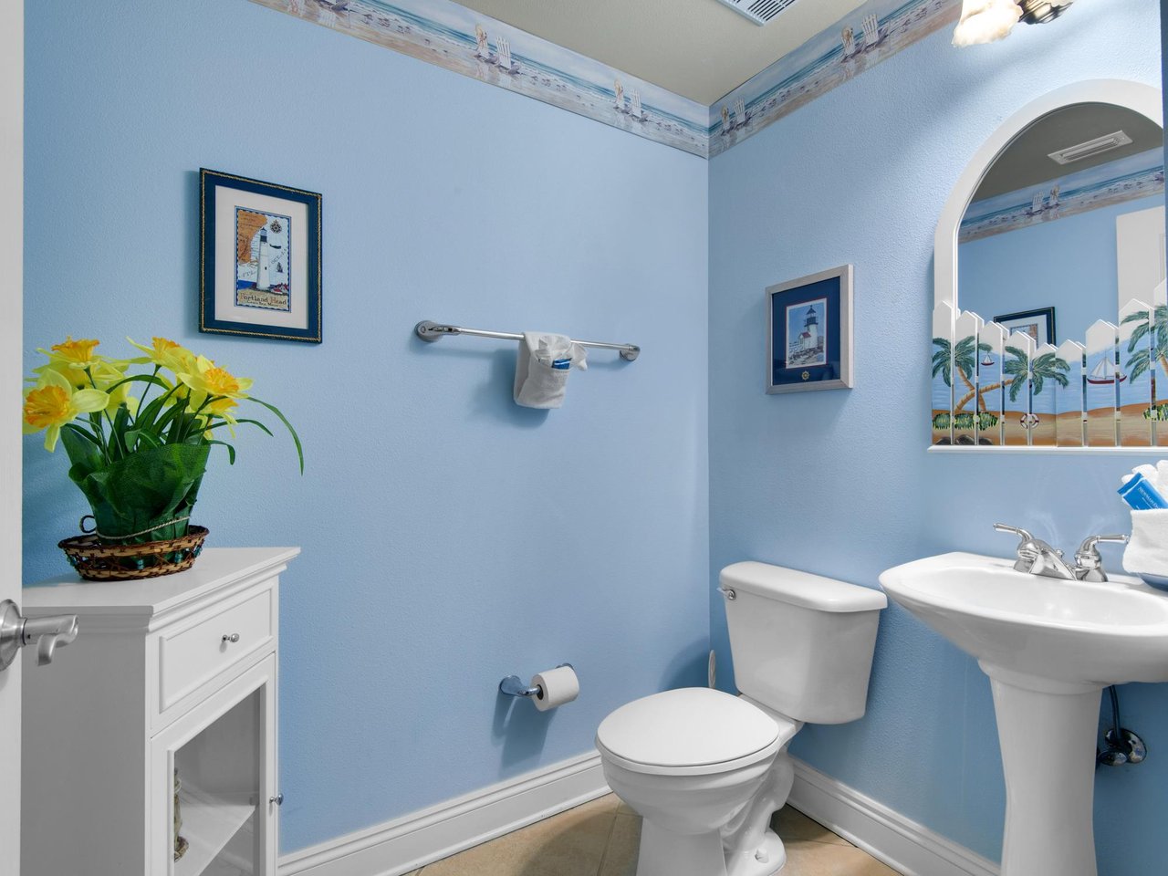 Freshen up in this convenient half bath featuring crisp white fixtures and nautical artwork