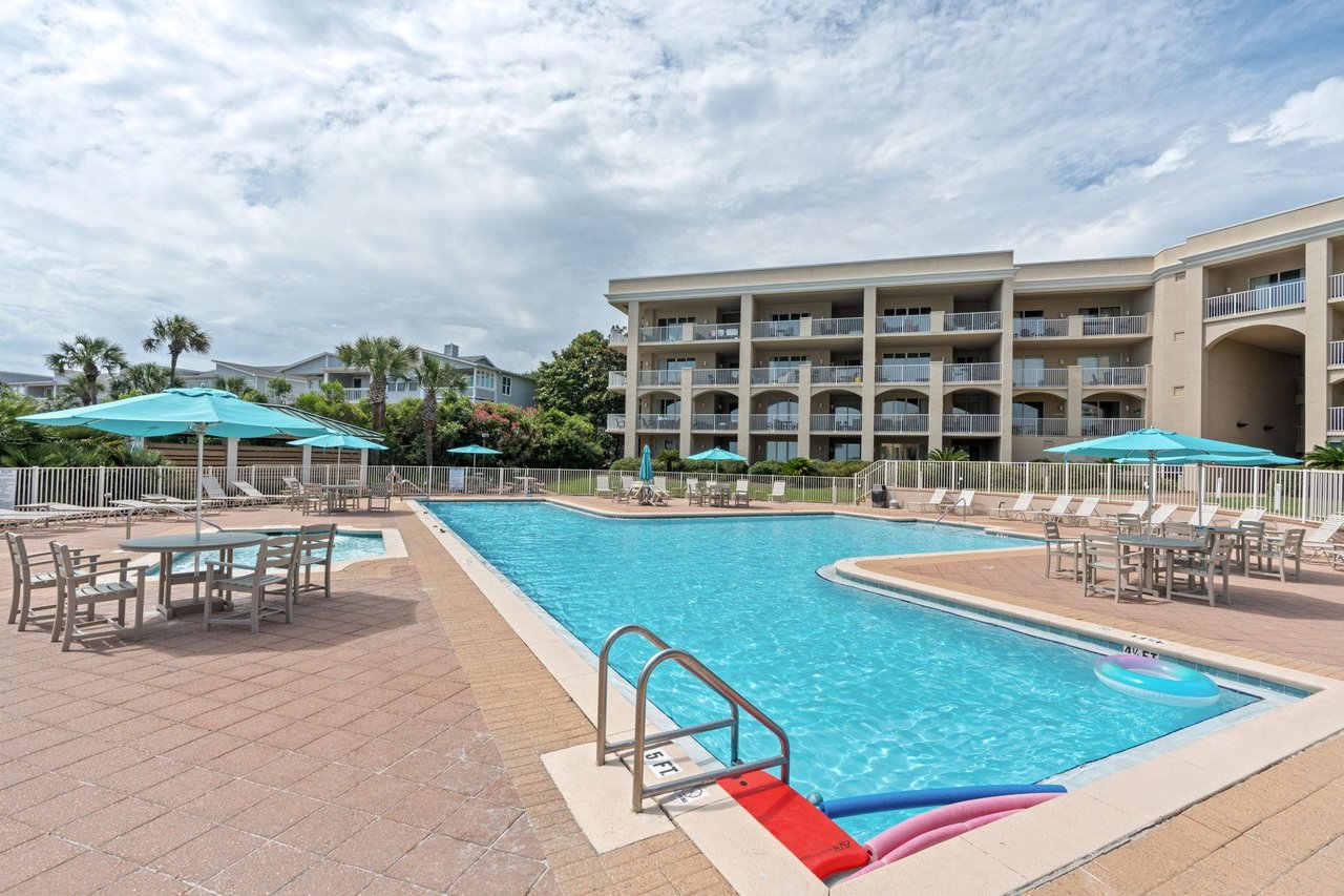 The sparkling outdoor pool is surrounded by comfortable lounge seating and shaded umbrellas, perfect for a refreshing swim or relaxing poolside with a good book.