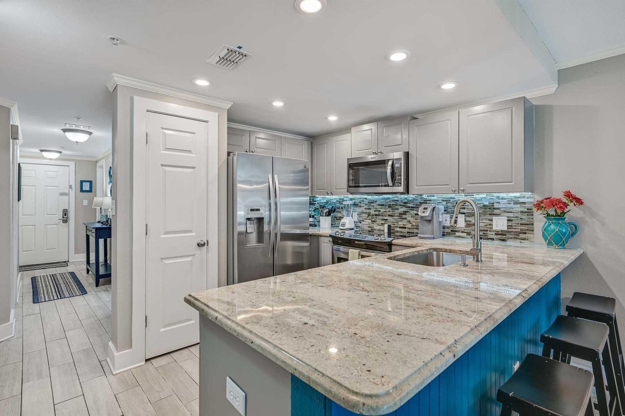 Gather around the generous island with granite countertops and gleaming stainless appliances. Your dream vacation kitchen awaits, complete with modern touches and colorful coastal accents.