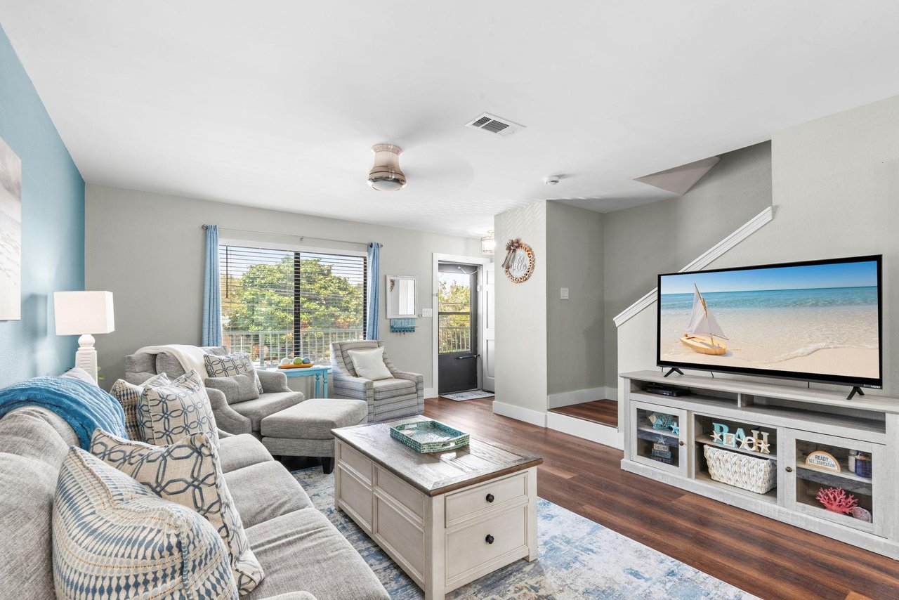 Step into your bright living space with cozy seating, and natural light streaming through doors that lead to your private outdoor area.