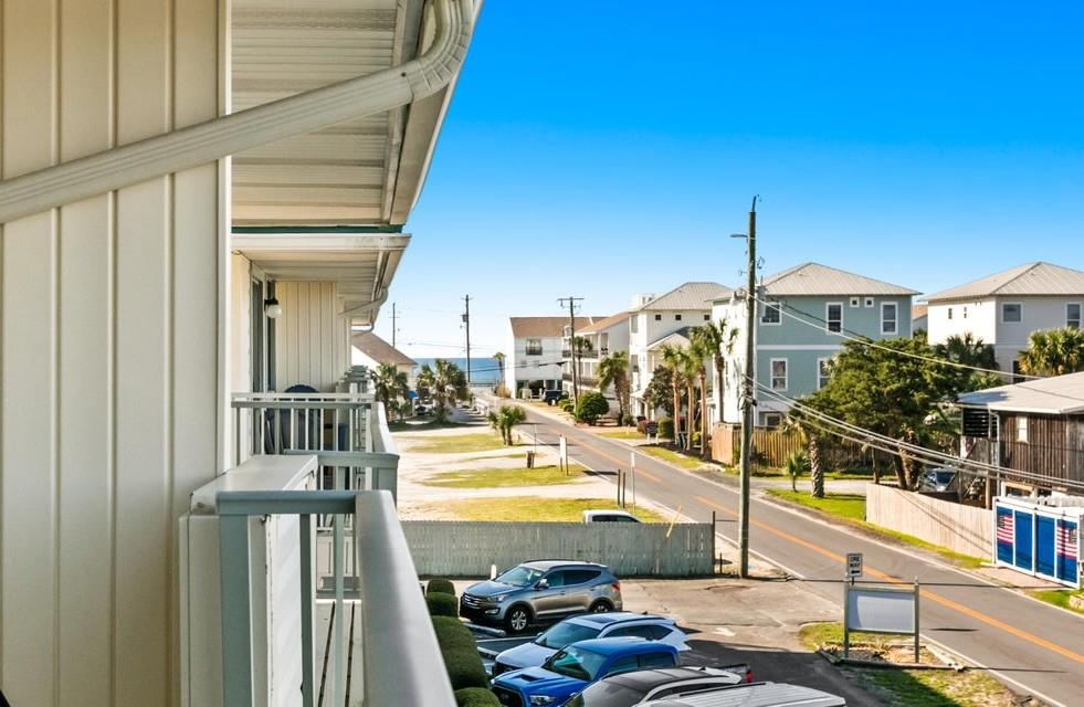 A bright, clear day frames the coastal neighborhood with palm trees and colorful homes lining the road. This vacation home sits in a welcoming residential area near the beach.