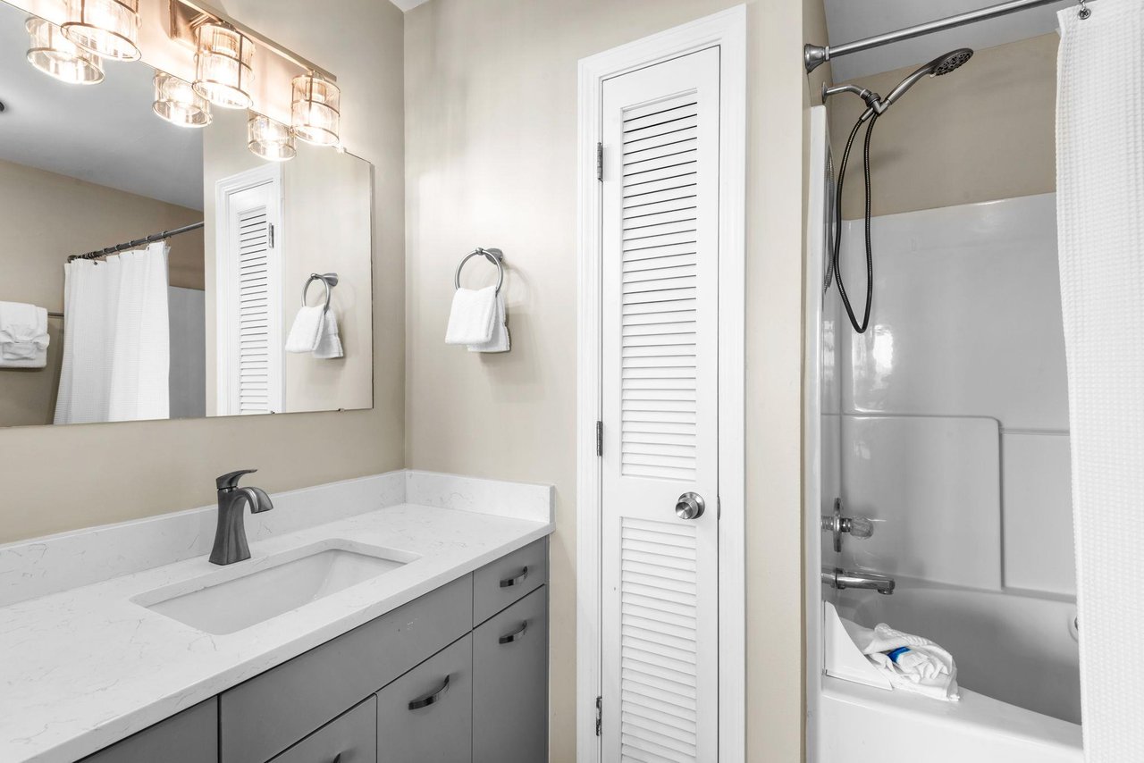 Your private bathroom blends calm neutrals with thoughtful finishes—bright vanity lights, sleek fixtures, and fresh towels await you.