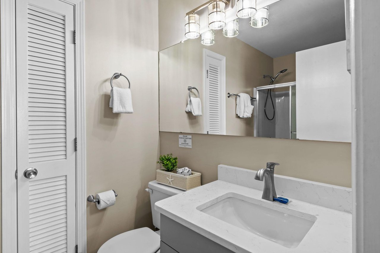 Step into your private bathroom, where soft lighting and coastal touches create a calming retreat. Fresh towels await, and modern fixtures make your stay effortless.