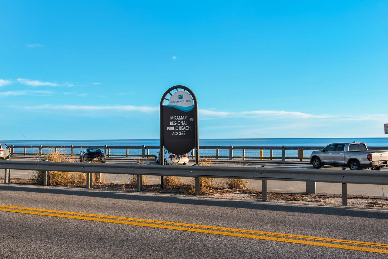 Miramar Regional Public Beach Access sign marks the nearby beach entrance along the coast under clear blue skies.