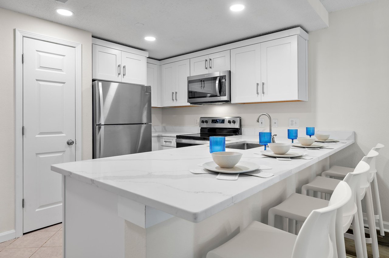 Gather around your sleek marble island, fully equipped for easy meal prep and casual dining together in this bright, modern kitchen.