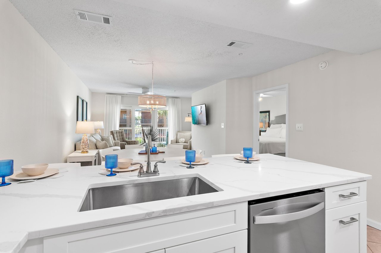 Sleek white countertops and stainless appliances set the stage for easy meal prep, with the bright, inviting living space and your restful bedroom just steps away.