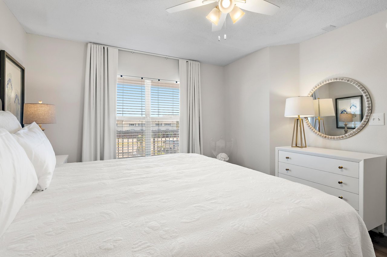This serene Guest bedroom invites you to unwind on plush bedding, with thoughtful touches and a ceiling fan overhead to keep you comfortable.