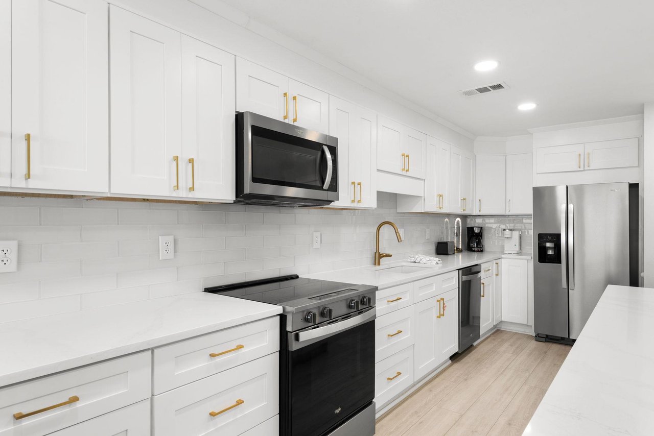 Your bright, modern kitchen awaits with sleek white cabinetry, gold fixtures, and stainless steel appliances—perfect for whipping up meals while you enjoy your getaway.