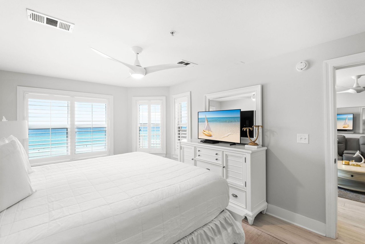 Wake up to stunning ocean views framed by bright shuttered windows in your serene coastal bedroom, complete with a gentle ceiling fan and beachinspired touches.