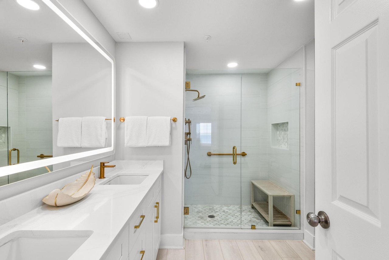 Step into a spalike bathroom with double vanities, bright LED lighting, and a spacious walkin shower featuring elegant gold fixtures and calming tile that invites you to unwind in comfort.