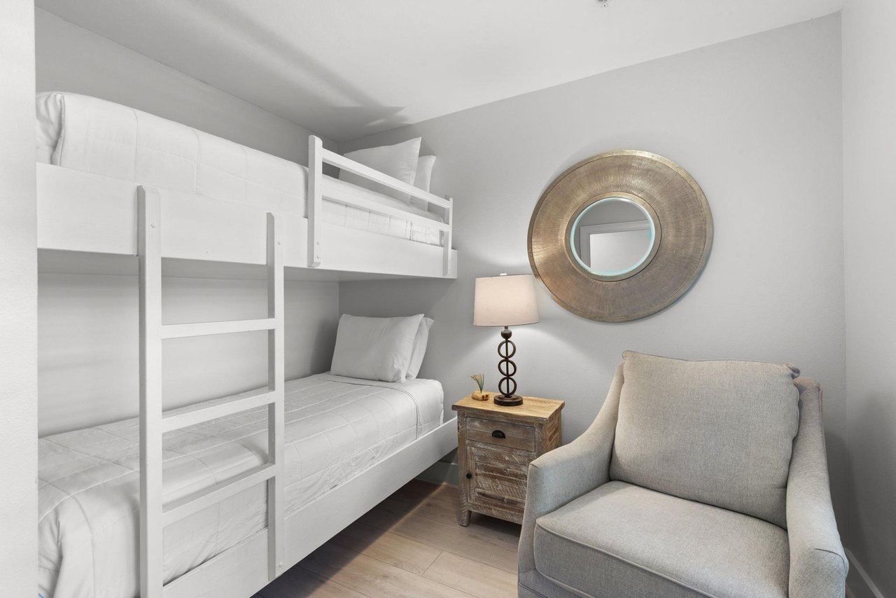 Youll find cozy sleeping arrangements with this spacesaving bunk bed setup, thoughtfully designed with crisp white linens and a comfortable chair for unwinding after your days adventures.