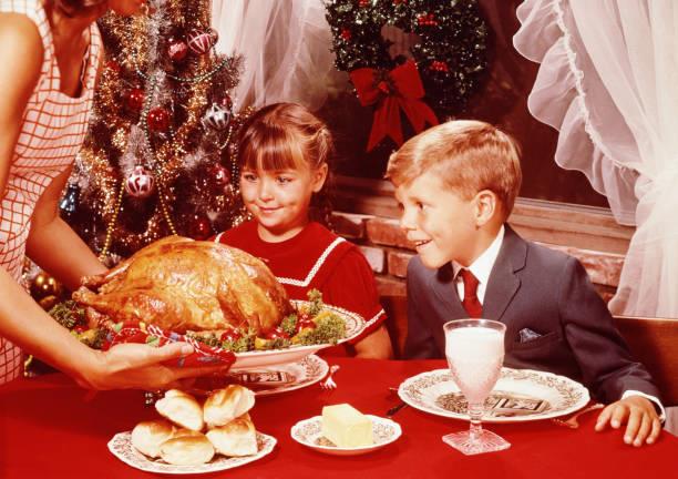 a woman and two children sitting at a table with food